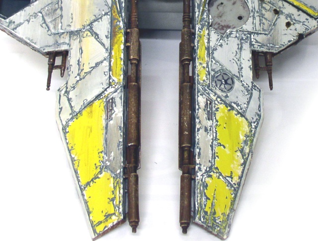 Détail des ailes grises et jaunes vieillies avec canons rouillés de la maquette d'épave spatiale