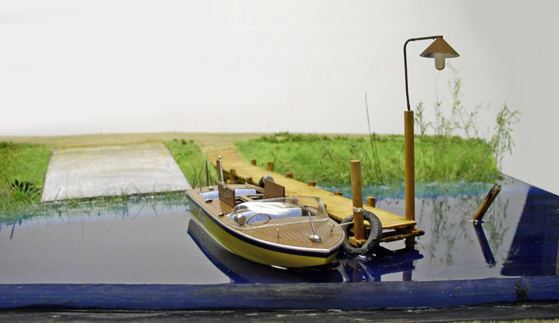 Maquette de bateau en bois amarré à un ponton sur une eau en résine