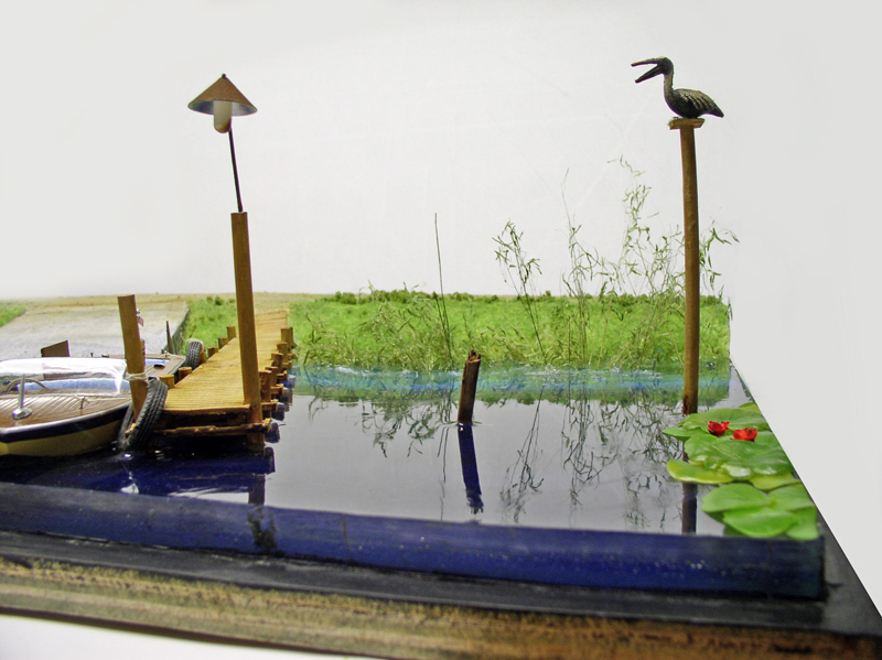 Diorama d'étang en résine avec ponton, barque, lampadaire, oiseau perché et nénuphars