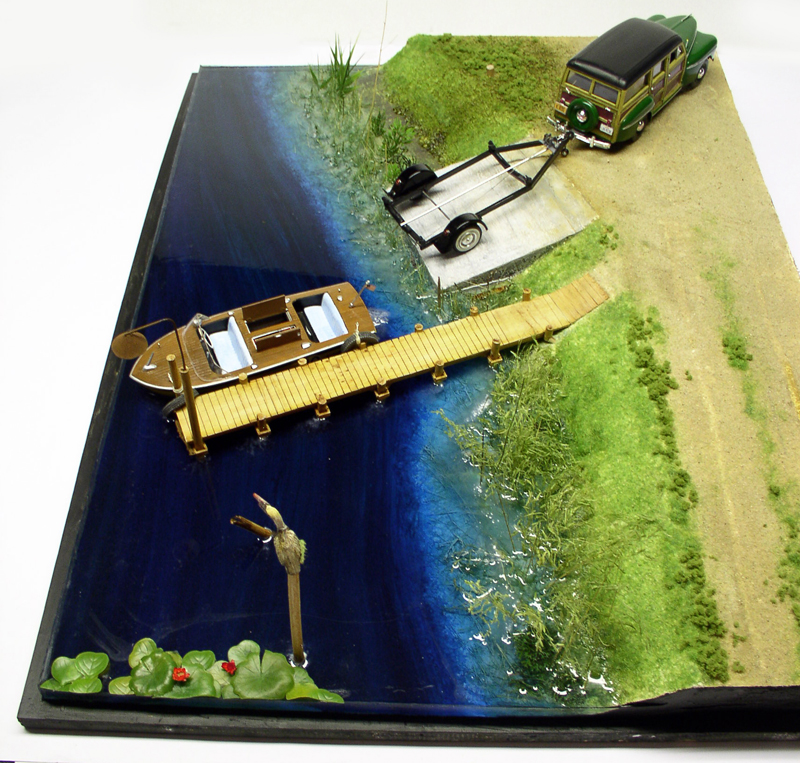 Diorama avec eau en résine bleue, bateau au ponton, voiture et remorque sur la berge