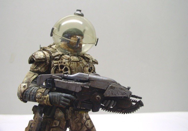 Figurine maquette de Marcus Fenix en armure avec casque sphérique tenant un fusil tronçonneuse