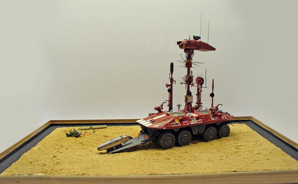 Maquette du transporteur Mars Odyssey rouge à six roues sur diorama de sable martien