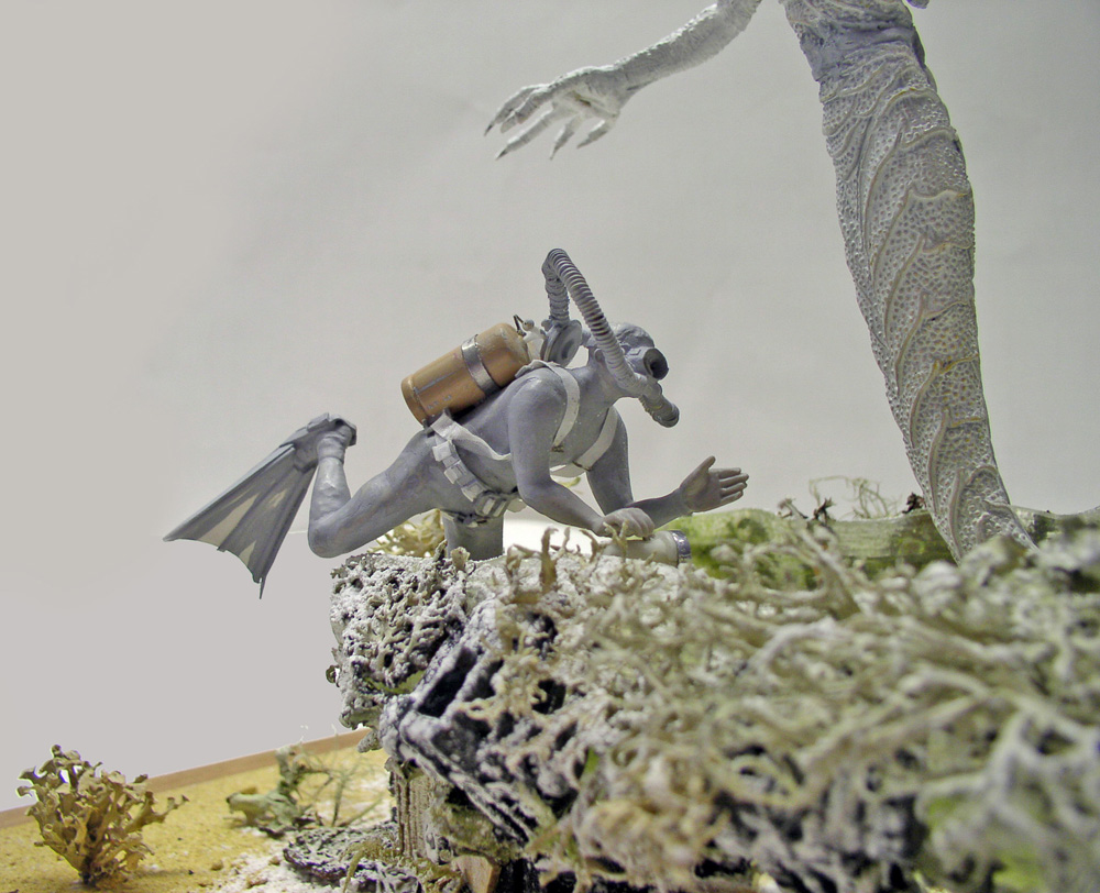 Figurine de plongeur sous-marin avec bouteille, menacé par la griffe d'un démon marin