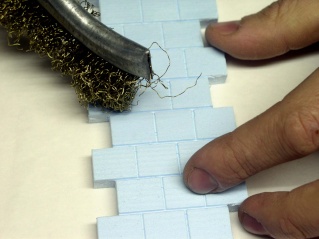 Brossage métallique d'un mur en polystyrène extrudé gravé d'imitation de briques
