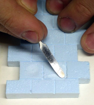 Gravure de joints de briques dans du polystyrène extrudé bleu avec un outil métallique