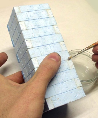 Mur en polystyrène extrudé sculpté en briques peintes en bleu, application d'enduit au pinceau