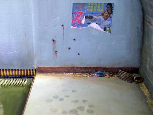 Mur de diorama en polystyrène extrudé peint, avec affiche déchirée et impacts de balles simulés
