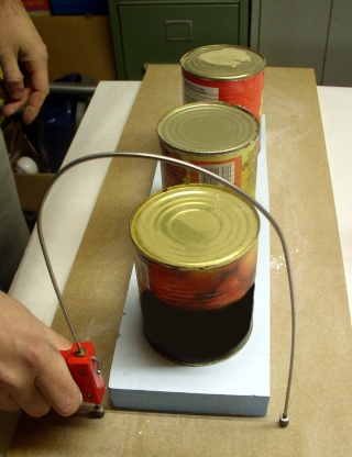 Découpe d'une plaque de polystyrène extrudé au fil chaud, guidé par des boîtes de conserve