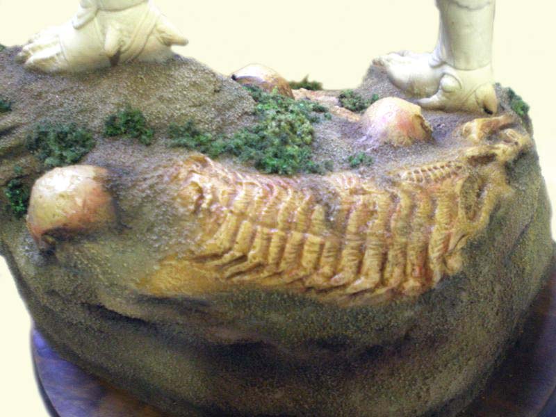 Socle de diorama Predator avec squelette fossilisé sculpté dans la roche sableuse et végétation