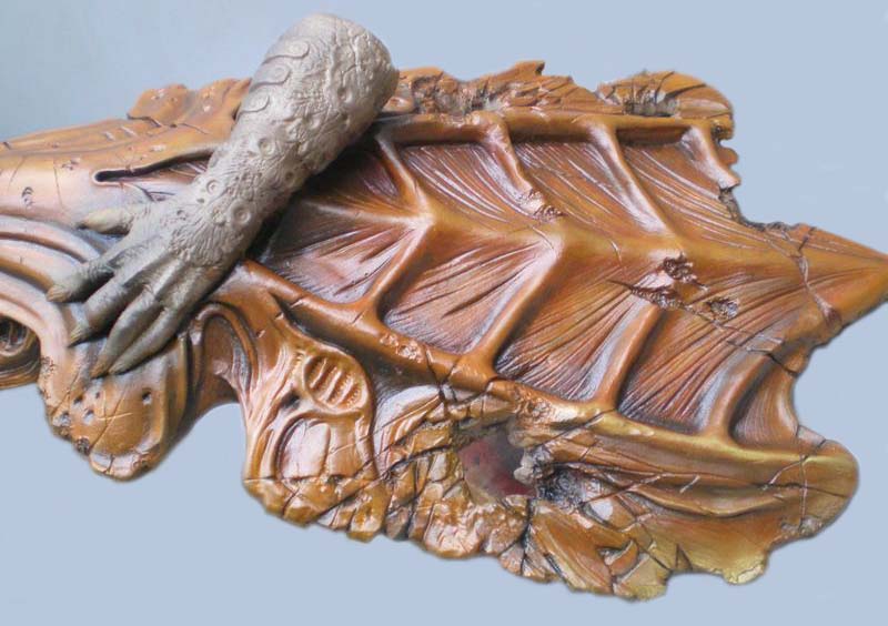 Détail d'un socle de diorama Predator avec carapace sculptée et main griffue posée dessus