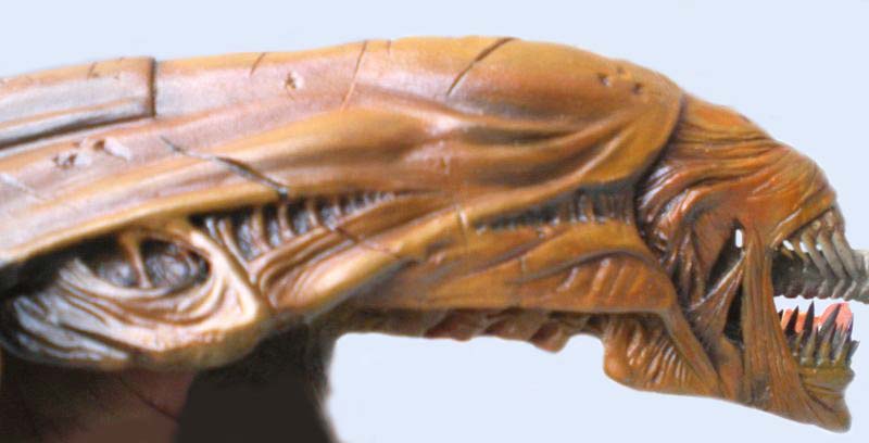 Profil de la tête sculptée d'un xénomorphe aux mâchoires acérées, peinture brune dégradée