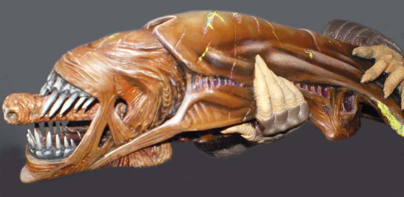 Maquette de créature Predator brune aux mâchoires dentées et griffes saillantes vue de profil