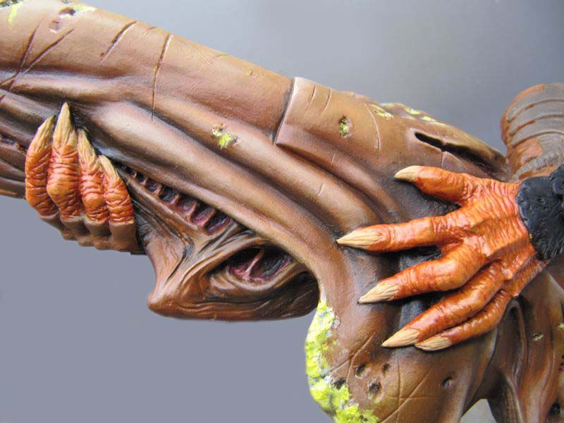 Tête de figurine Predator peinte montrant mâchoires ouvertes et mains griffues orange agrippant le visage