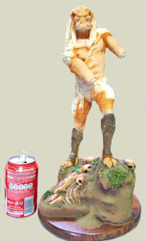 Figurine Predator non peinte sur socle décoré de crânes, à côté d'une canette pour l'échelle