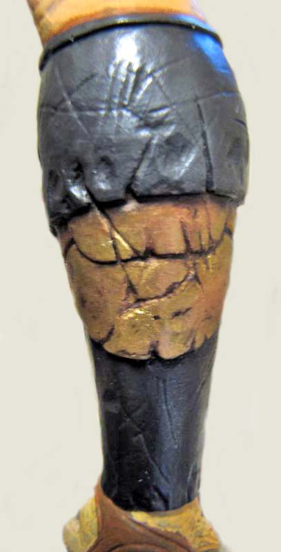 Détail de la jambe peinte d'une figurine Predator avec armure noire et écailles dorées