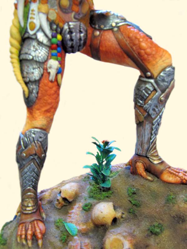 Détail des jambes de la figurine Predator sur un socle rocheux avec crânes et plante