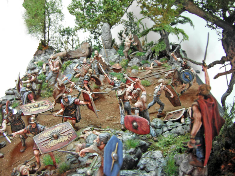 Diorama de bataille entre légionnaires romains et guerriers barbares sur un terrain rocheux boisé