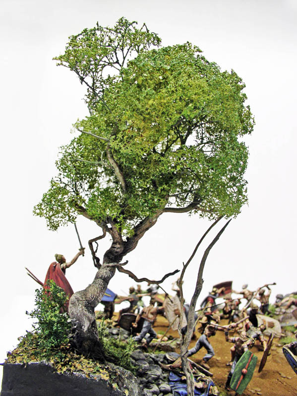 Diorama de bataille romaine avec arbre miniature feuillu surplombant des figurines de soldats combattant