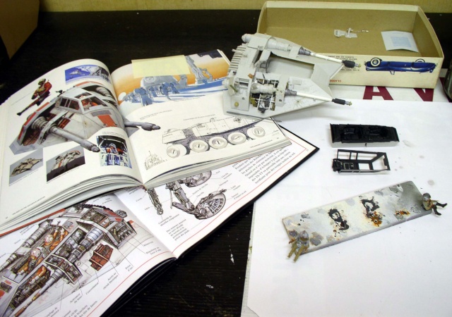 Maquette de Snowspeeder en montage sur établi avec livre de documentation ouvert et pièces peintes