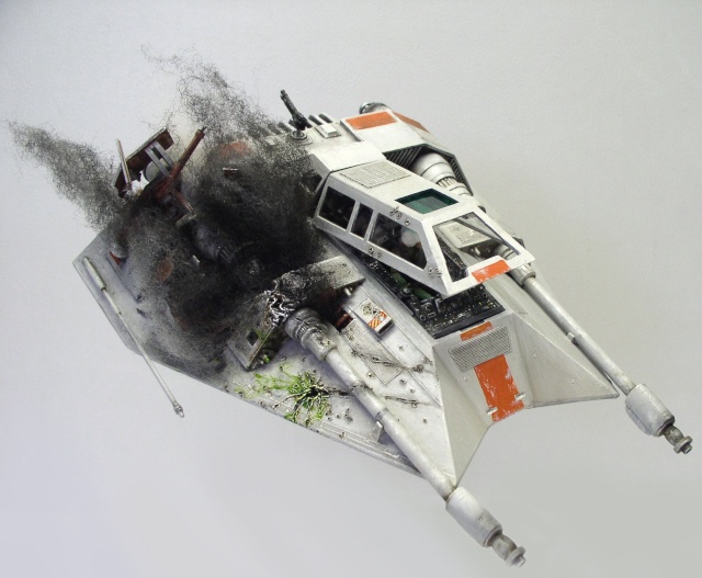 Maquette de Snowspeeder gris et orange écrasée au sol avec effet de fumée noire