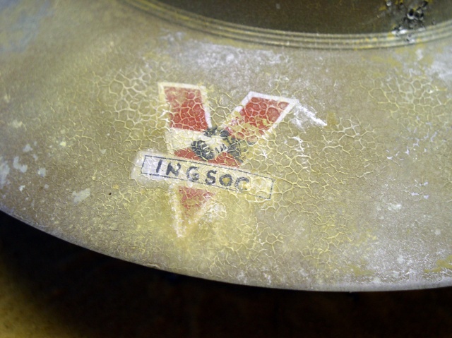 Détail de la coque vieillie avec emblème rouge et marquage INGSOC en patine craquelée