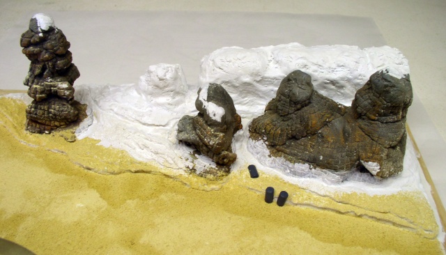 Diorama de maquettisme représentant des rochers enneigés sur une plage de sable