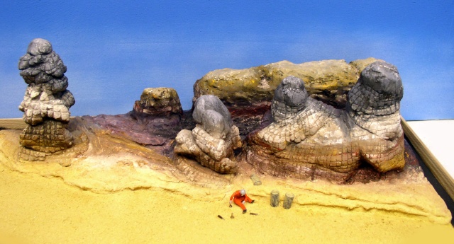 Diorama désertique de maquette avec rochers stratifiés et petit personnage en combinaison orange