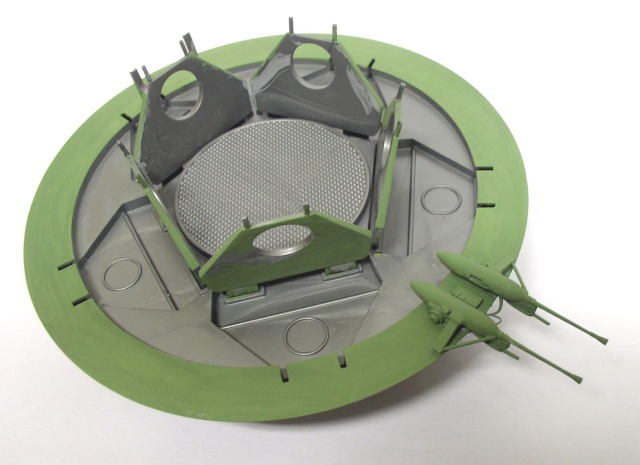 Maquette de soucoupe volante verte et grise en cours d'assemblage avec structures internes détaillées