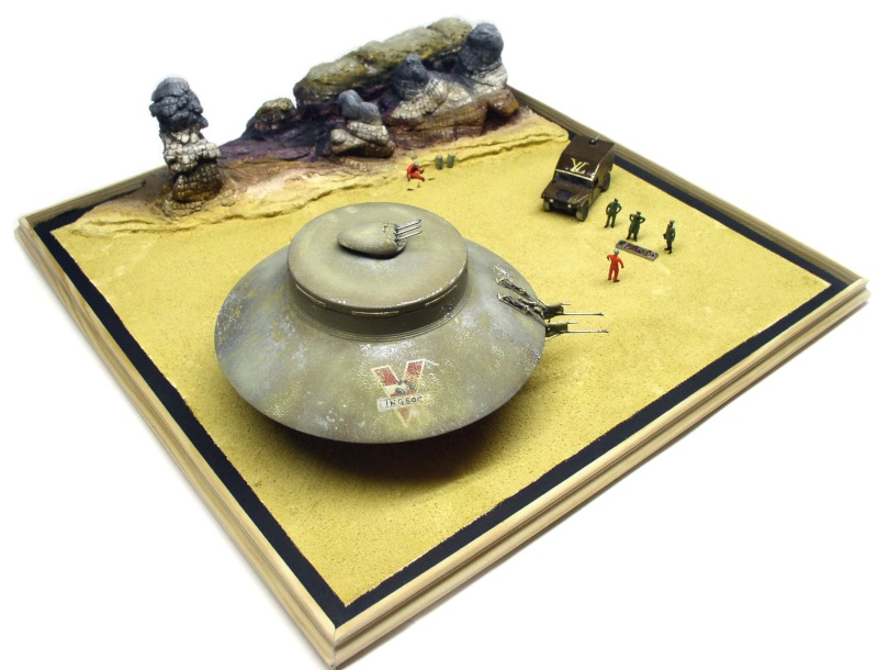 Maquette de soucoupe volante INGSOC posée sur un diorama désertique avec rochers, camion militaire et figurines
