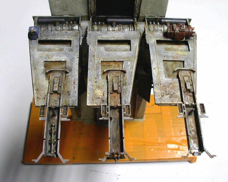 Maquette Space Chevy détaillée montrant trois moteurs métalliques vieillis sur socle orange
