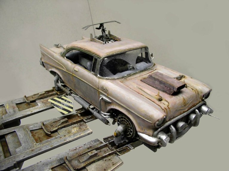 Maquette de Chevrolet 1957 vieillie et rouillée posée sur une plateforme métallique futuriste
