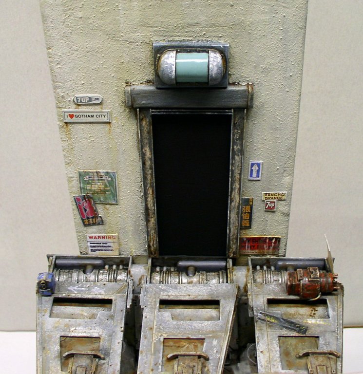 Diorama futuriste vieilli avec porte sombre, affiches et machines métalliques patinées de la maquette Space Chevy