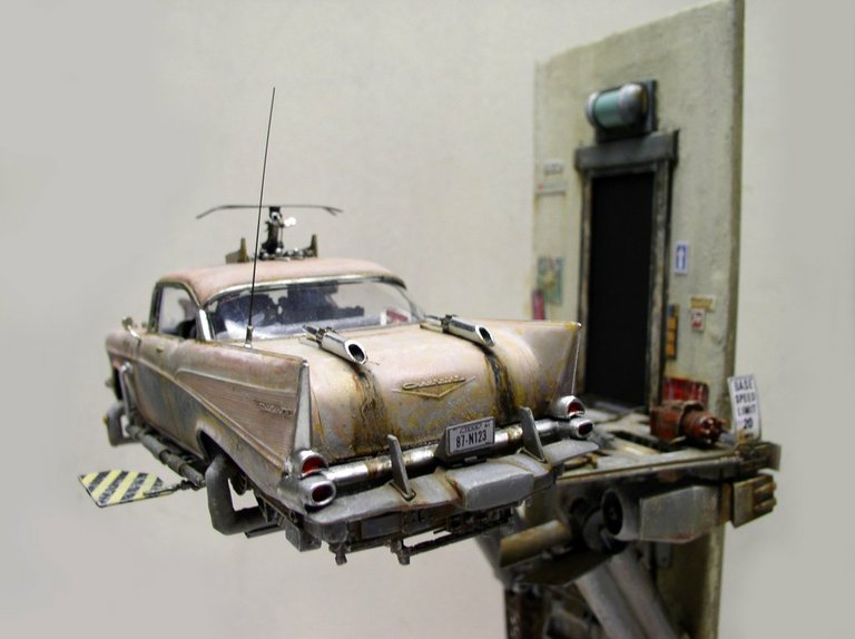 Maquette de Chevrolet vieillie volante avec réacteurs, posée sur une plateforme près d'une porte