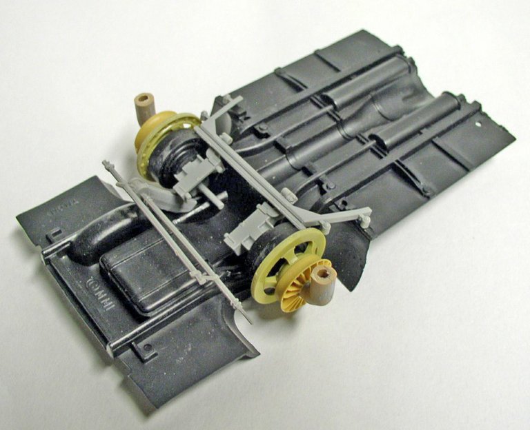Châssis de maquette Space Chevy avec pièces grises et éléments mécaniques jaunes en cours d'assemblage