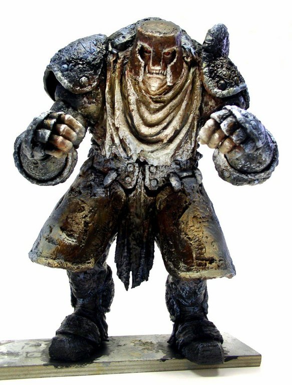 Figurine peinte d'un guerrier monstrueux à tête de crâne, poings serrés, sur socle