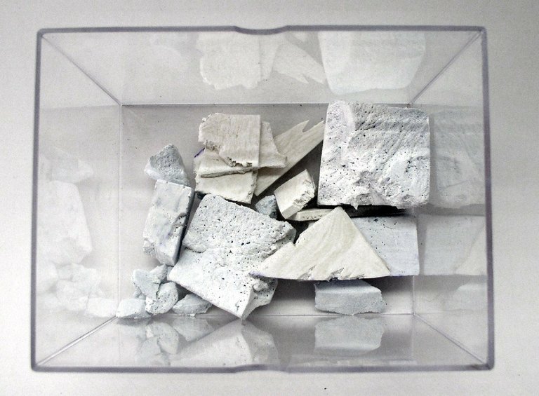 Morceaux de plâtre blanc fragmentés rassemblés dans une boîte en plastique transparente