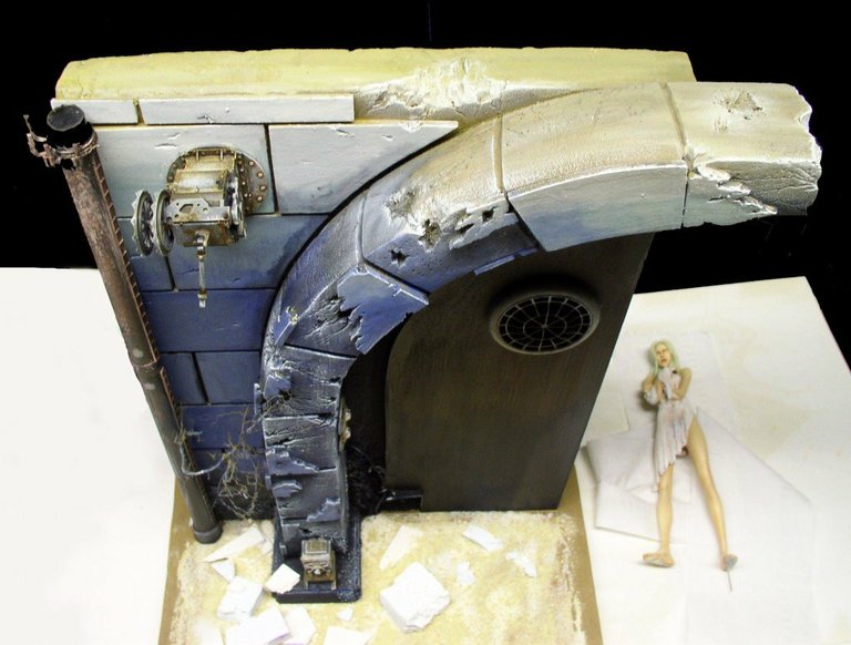 Diorama mural en pierre bleutée avec arche et figurine féminine peinte à droite