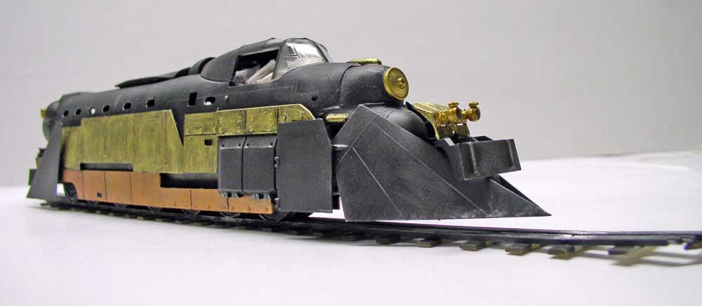 Maquette de locomotive blindée noire aux plaques laiton et cuivre sur rails