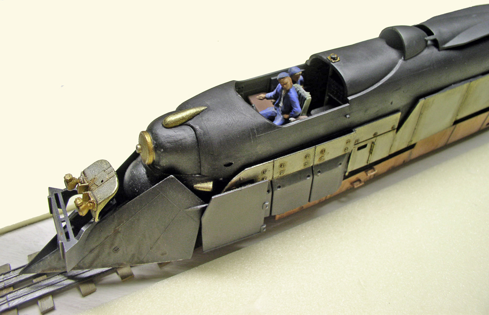 Maquette de locomotive blindée noire avec figurines dans la cabine et chasse-pierres avant