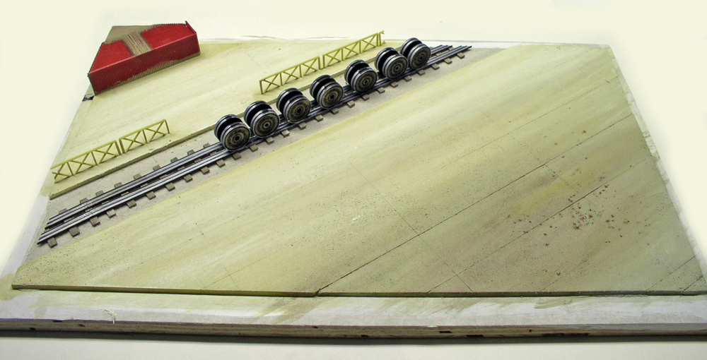 Train de roues métalliques sur rails et maquette de quai en construction pour diorama ferroviaire