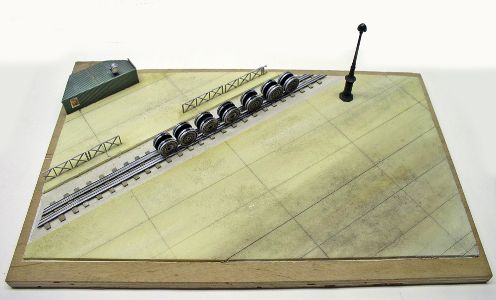 Essieux à roues métalliques alignés sur une voie ferrée de diorama avec lampadaire et bâtiment