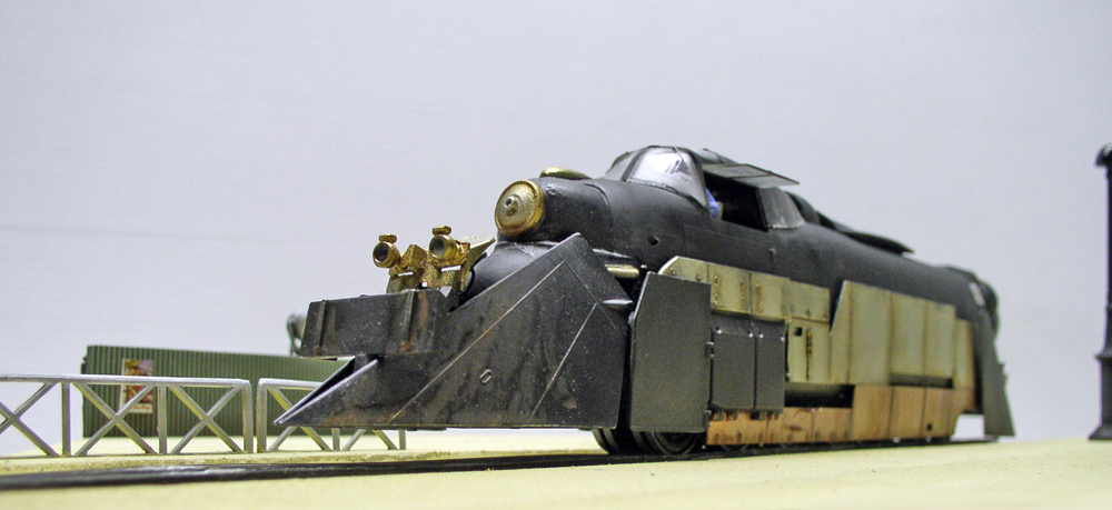 Maquette de locomotive blindée noire avec chasse-pierres anguleux et détails laiton dorés sur rails
