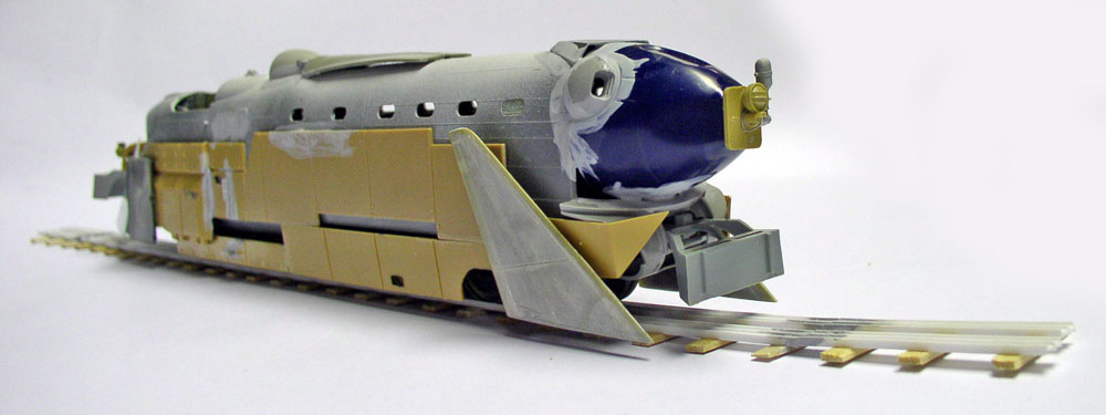 Maquette de locomotive blindée steampunk en montage sur rails, nez bleu et chasse-pierres