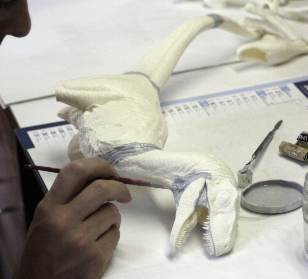 Application d'une sous-couche au pinceau sur la maquette de Velociraptor blanche non peinte