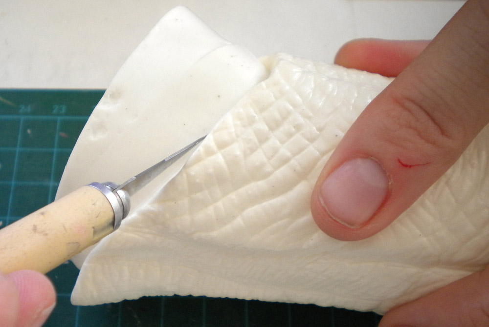 Découpe au couteau de modélisme d'une pièce blanche texturée tenue à la main
