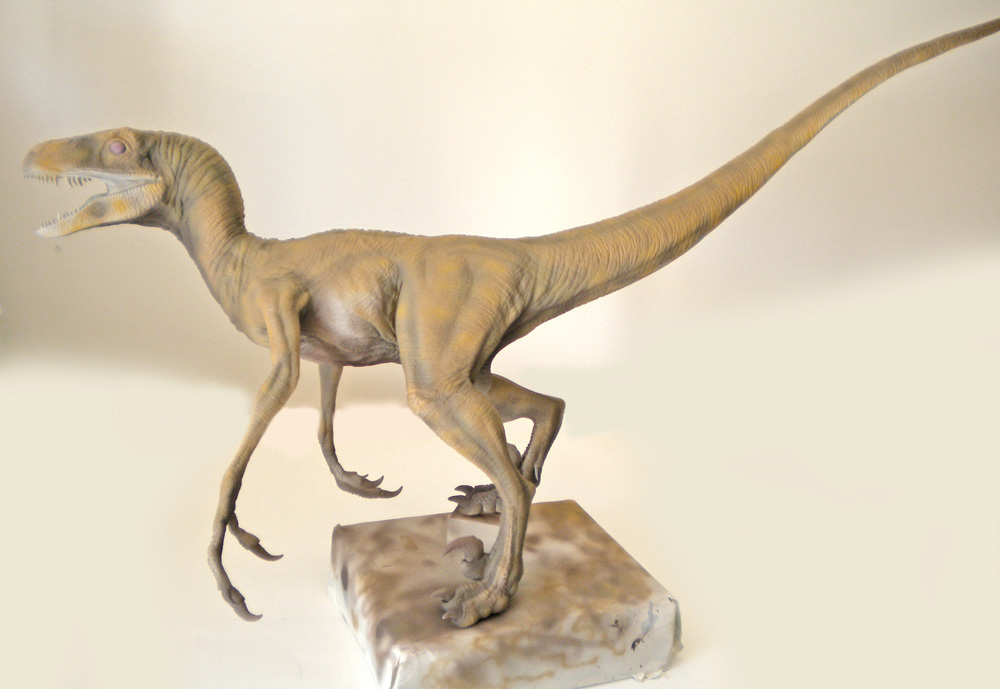 Maquette de Velociraptor peinte en beige, gueule ouverte, posée sur un socle clair