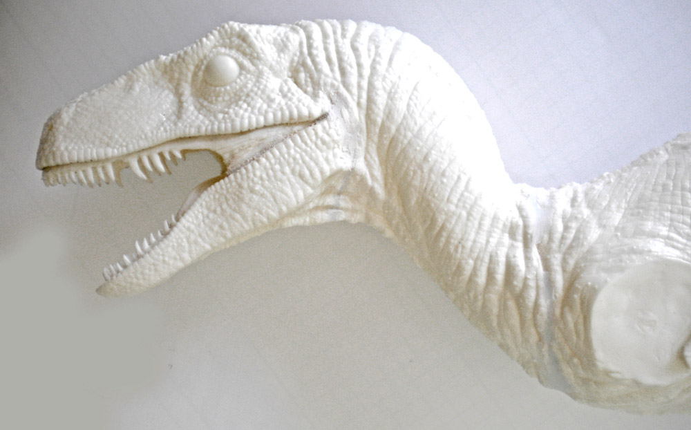 Tête et cou sculptés d'un Velociraptor gueule ouverte, maquette blanche aux écailles détaillées non peinte