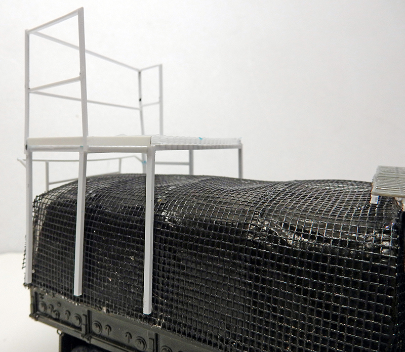 Plateforme blanche en construction montée sur la bâche grillagée noire d'un camion miniature