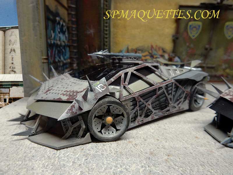 Diorama urbain avec voiture de police futuriste blindée à pointes devant murs tagués