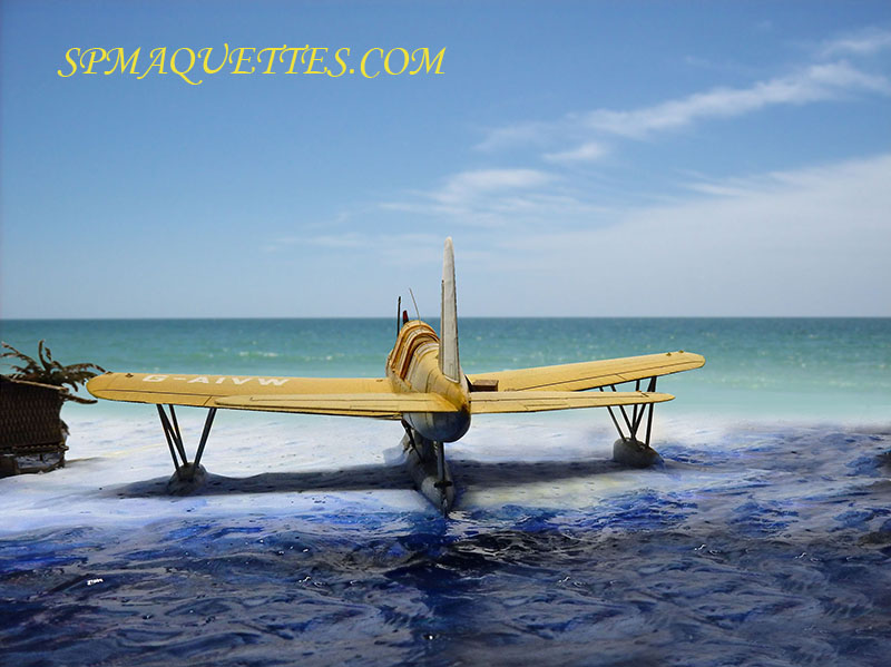 Diorama du Vought OS2U Kingfisher jaune sur flotteurs, échoué dans les vagues d'une plage tropicale